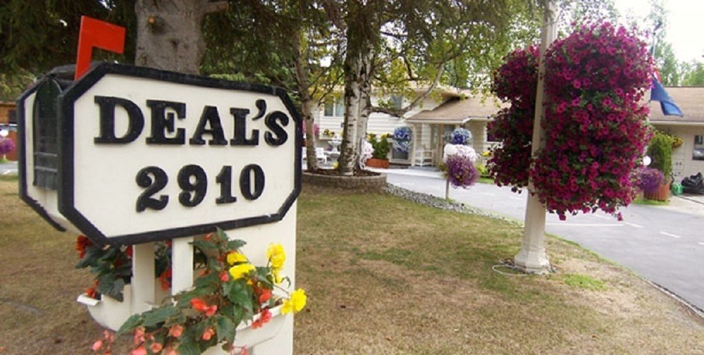 A house number sign for 'Deal's 2910' with a mailbox and flowers.