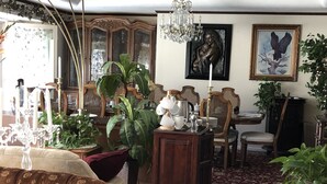 Un salón tradicional con un sofá grande, una mesa de comedor con sillas, una araña y varios objetos decorativos.