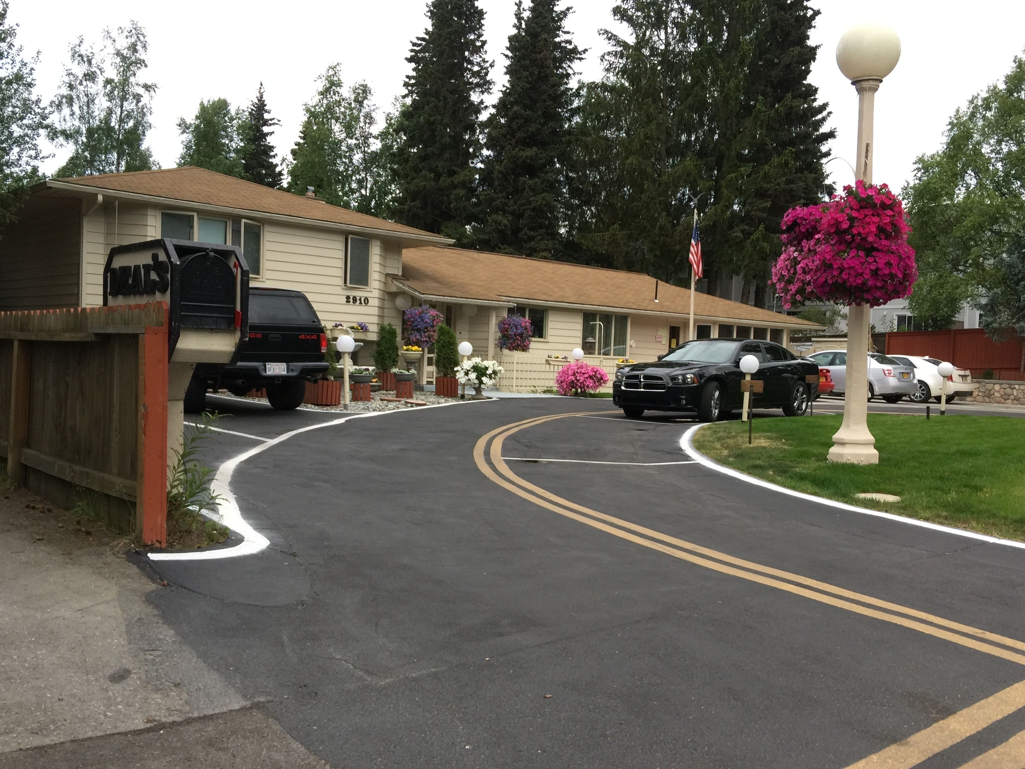 Un motel avec une allée incurvée, des voitures garées et une boîte aux lettres portant l'inscription « JACKALS ».