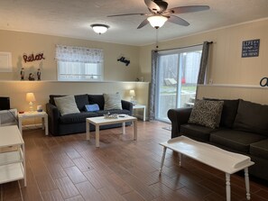 Relax in this stylish living room with a ceiling fan, large window, and sliding glass door leading to an outdoor area.
