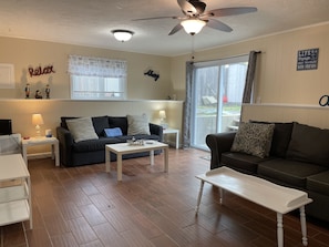Relax in this stylish living room with a ceiling fan, large window, and sliding glass door leading to an outdoor area.