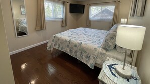 A bedroom with a bed, a TV mounted on the wall, and a bedside lamp.