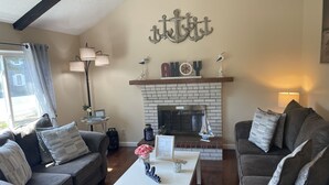 A living room with two grey sofas, a white coffee table, and a fireplace with a brick surround.