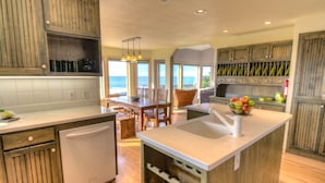 A kitchen with wooden cabinets, a central island, and a view of the ocean. - Amazing Ocean Views in Yachats! Modern Decor! Dog Friendly! (Yachats)
