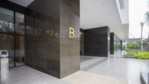 A modern building entrance with a 'B' sign, a reception desk, and a glass door.