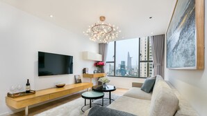 A modern living room with a large TV, a sofa, a coffee table, and a city view through the window.