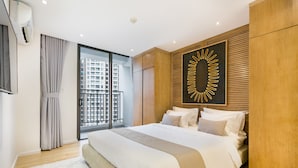 A modern bedroom with a large bed, a view of a cityscape through a sliding glass door, and a unique wall art piece.