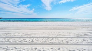 Una playa con arena blanca y un cielo azul despejado.