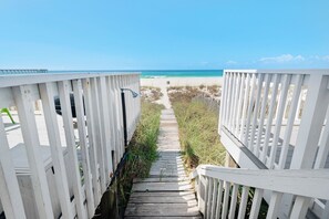 A wooden pathway leading to a beach, flanked by white railings.