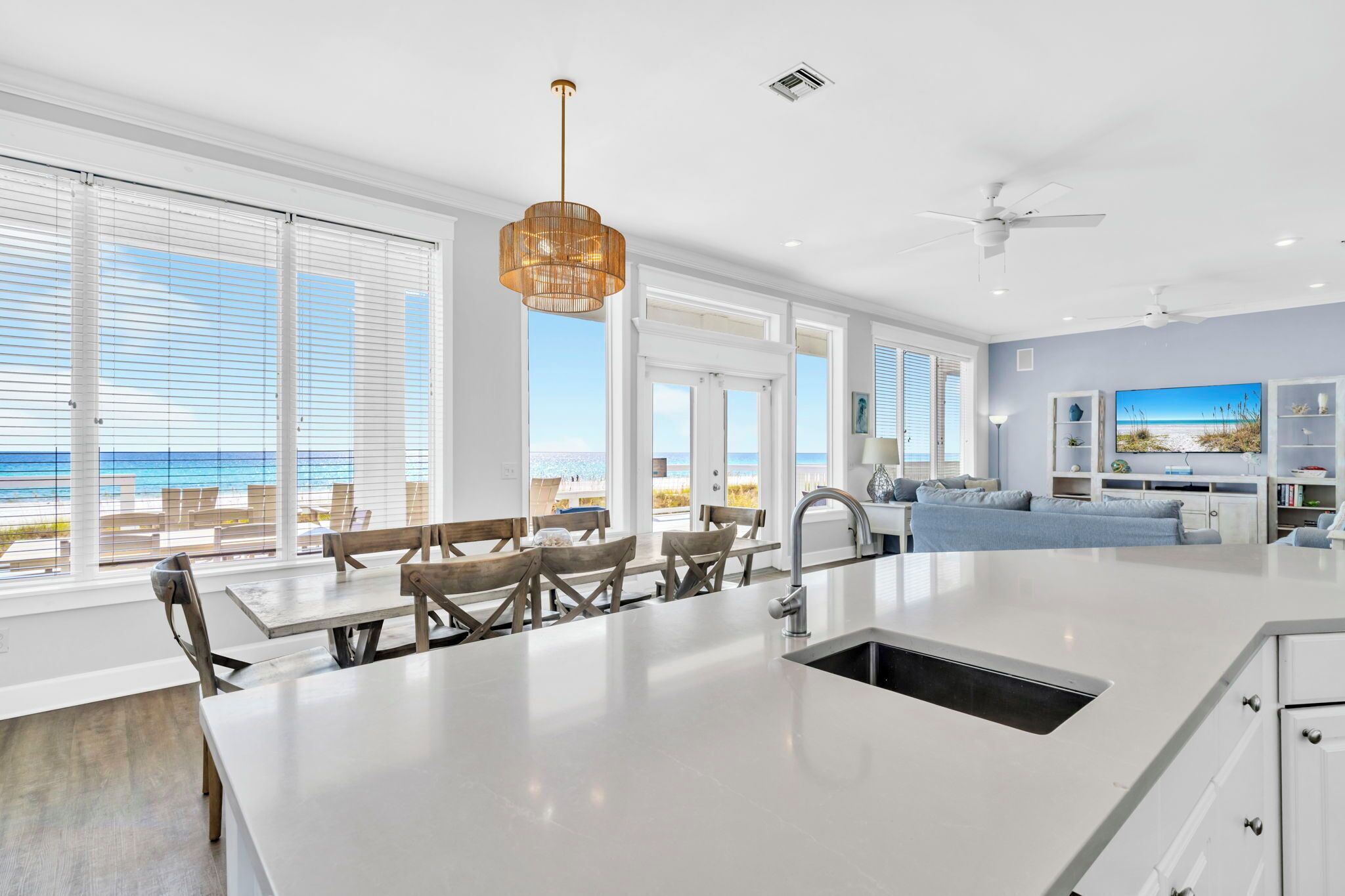 A spacious kitchen with a large island, white cabinetry, and a view of the beach.