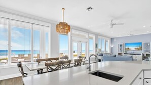 Una cocina espaciosa con una isla grande, muebles blancos y vista al mar.