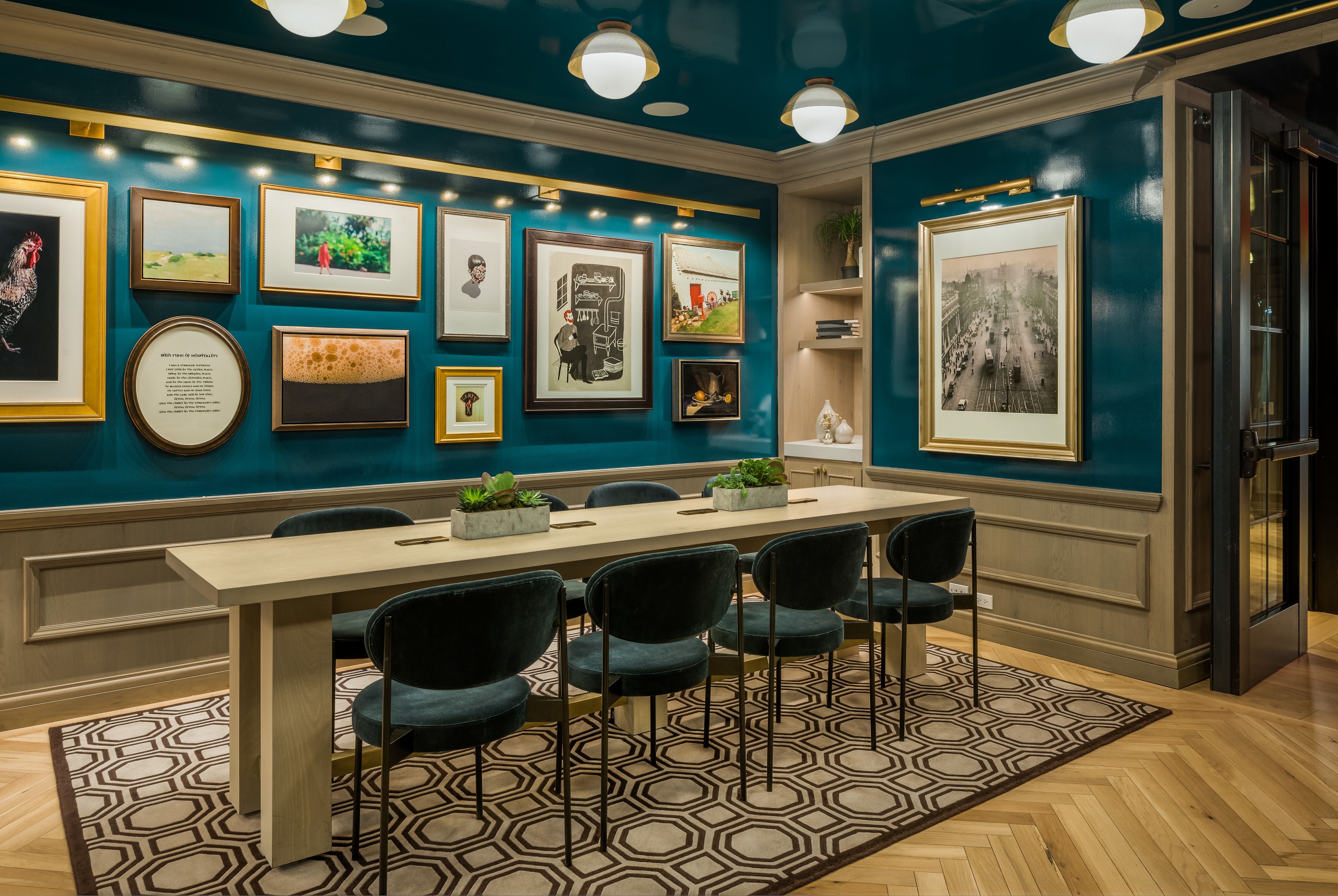 A conference room with a long table, six chairs, and framed pictures on the walls.