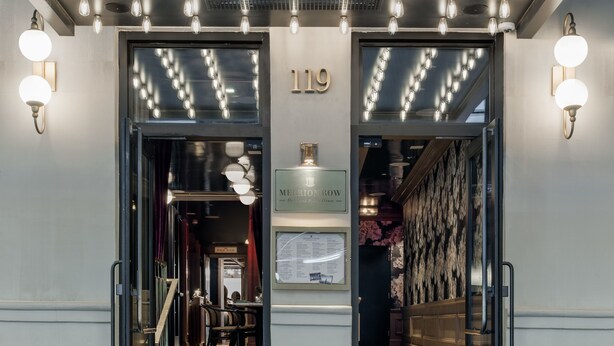 Entrada de l'Hotel MERRION ROW i Public House, amb façana negra, lluminàries de marquesina i una estoreta negra amb el nom de l'hotel.