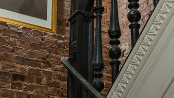 Un escalier avec des balustrades noires et un mur de briques.