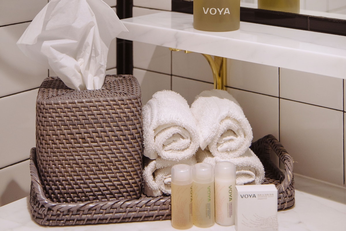A bathroom vanity with toiletries, a tissue box, and a mirror.
