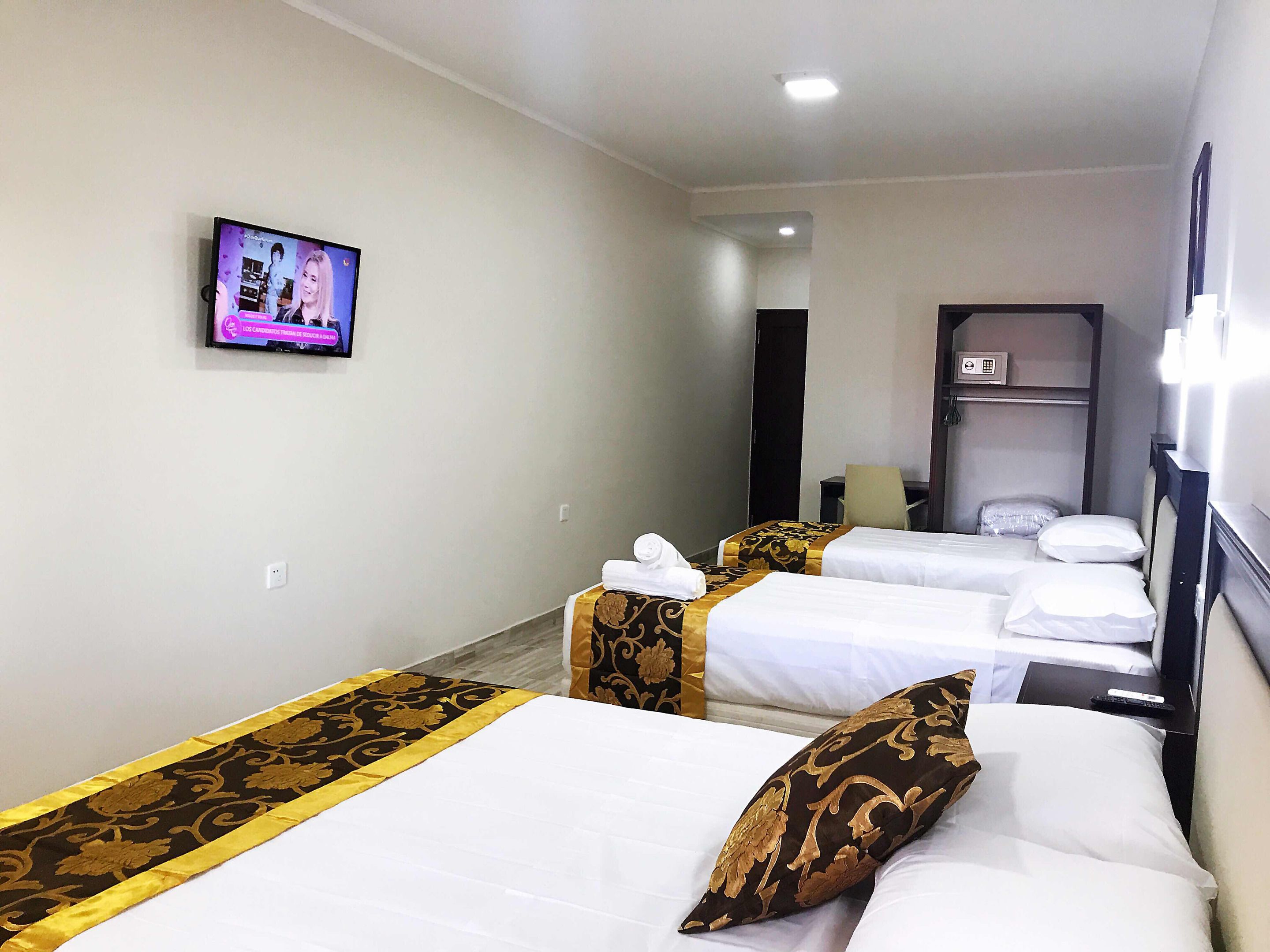 A hotel room with two beds, a television on the wall, and a desk with a chair.