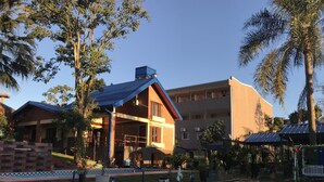 A hotel with a covered outdoor seating area, a swimming pool, and a large building with multiple floors. - Hotel Amayal (Puerto Iguazú)