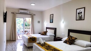 A hotel room with two beds, a balcony, and a view of greenery. - Hotel Amayal (Puerto Iguazú)