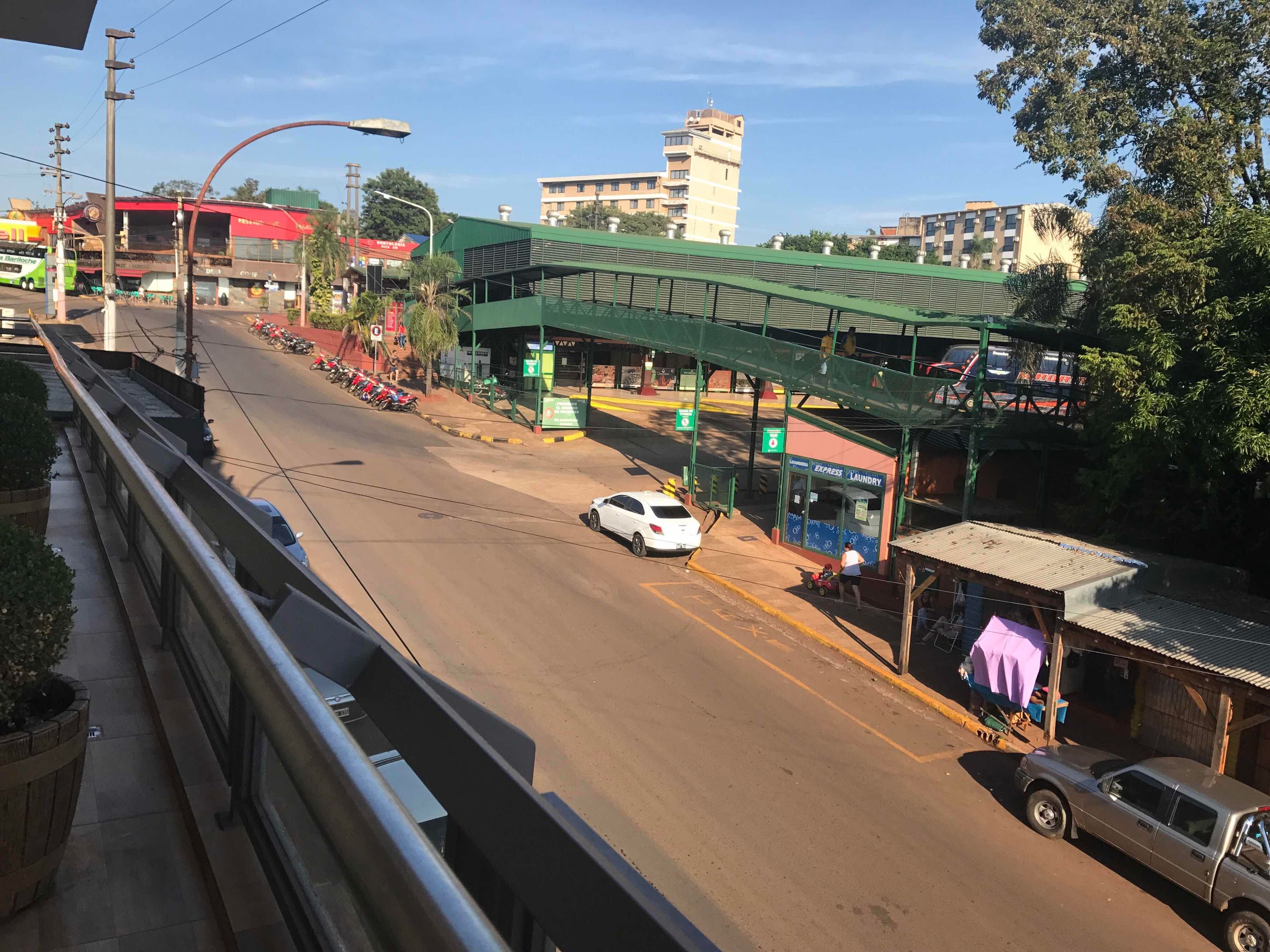 A street view with a green overpass, a white car, and a small building labeled "Express Laundry".