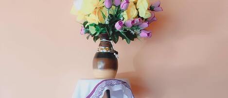 A vase with yellow and purple flowers on a metal table against a wall.