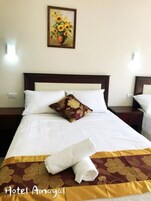 Habitación de hotel con una cama grande, un cojín estampado de flores, un jarrón con girasoles en la pared y una toalla sobre la cama.