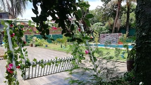 A garden with a wooden deck, a white fence, and various plants and flowers. - Hotel Amayal (Puerto Iguazú)
