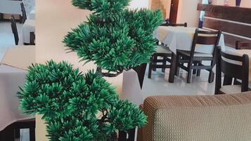Un espace repas avec des tables et des chaises, une plante en pot et un canapé.