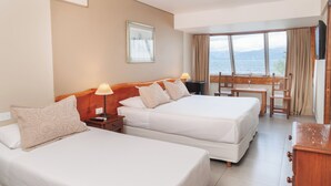 A hotel room with two beds, a desk, and a view of the sea. - Patagonia Hotel (San Carlos de Bariloche)