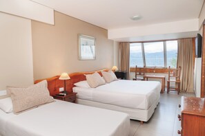 A hotel room with two beds, a desk, and a view of the sea. - Patagonia Hotel (San Carlos de Bariloche)