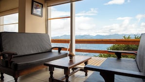 A balcony with a sofa and a table, overlooking a body of water and mountains. - Patagonia Hotel (San Carlos de Bariloche)