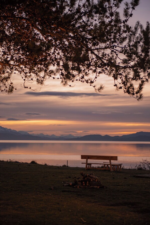 A bench and a fire pit in a natural setting with mountains in the background.
