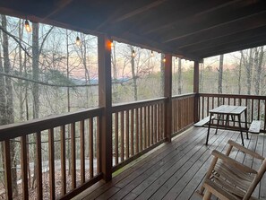 A wooden deck with a table and chairs, surrounded by trees. - Winter Special in quiet woods (Sevierville)
