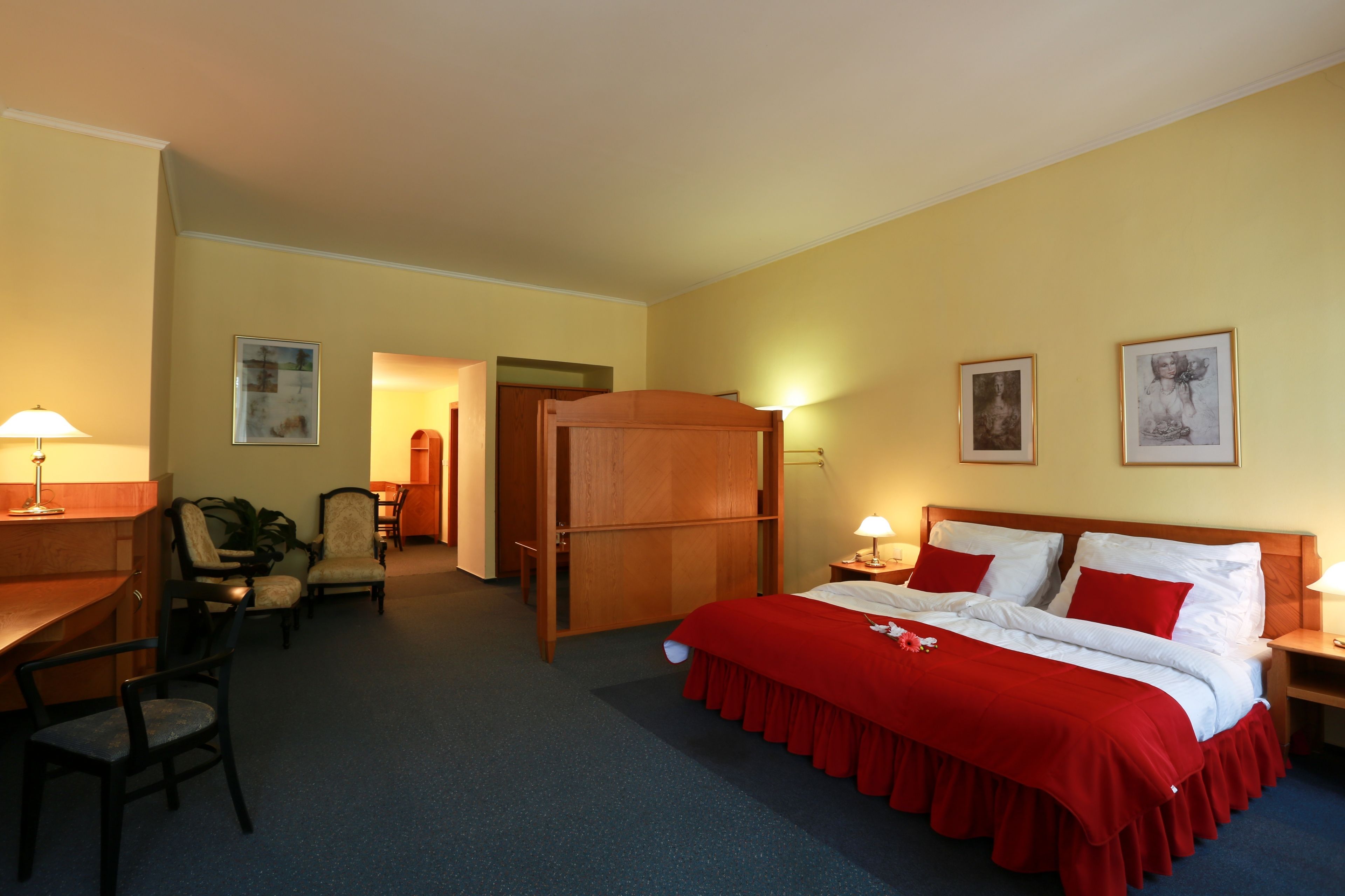 Una habitación de hotel con cama, dos mesitas de noche, un escritorio, una silla y un armario.