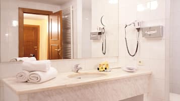 Ein Badezimmer mit Marmorwaschbecken, einem Spiegel und zwei an der Wand montierten Haartrocknern.