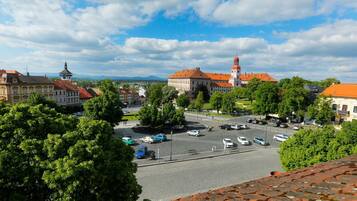 A view of a town square with historic buildings, a prominent tower, and a parking area.