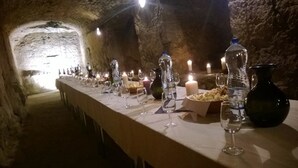 A long table set with glasses, candles, and bottles in a stone-walled room. - Hotel Magnolia Roudnice (Roundnice nad Labem)
