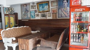 A restaurant interior with wooden furniture, a Coca-Cola refrigerator, and various framed pictures on the wall. - Queens Hotel (Chum Phae)