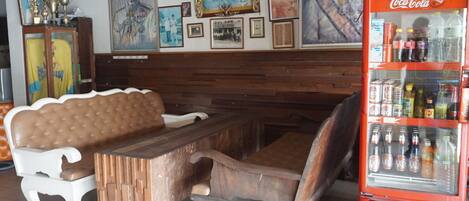 Interior de restaurante con mobiliario de madera, un refrigerador de Coca-Cola y varias fotografías enmarcadas en la pared.