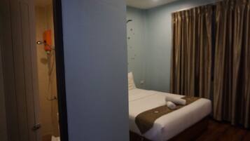 Quarto de hotel com cama, chuveiro e cortinas.
