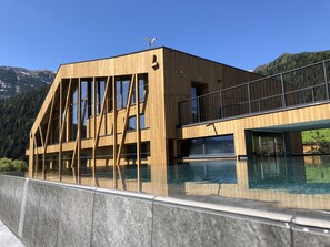 A modern wooden building with large windows and a pool. - Erlebnishotel Gassenhof (Racines)
