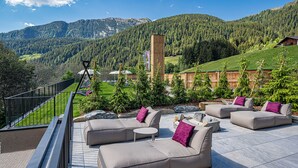 A terrace with outdoor seating and a mountain view. - Erlebnishotel Gassenhof (Racines)