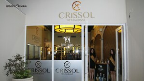 La entrada al restaurante Crissol, con una planta grande en maceta y un letrero con el nombre del restaurante.