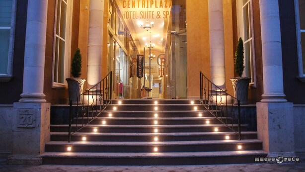 Imponente entrada con una escalera que conduce a una suite de hotel y spa, flanqueada por columnas e iluminada por luces.