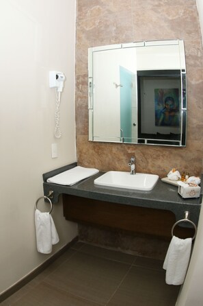 Un baño con un lavamanos blanco, un espejo y un perchero para toallas.