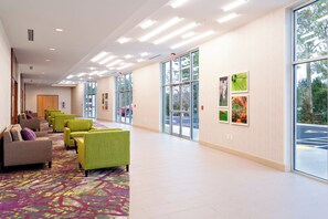 A hotel lobby with seating, large windows, and artwork on the walls. - Holiday Inn Tallahassee E Capitol - Univ by IHG (Tallahassee)