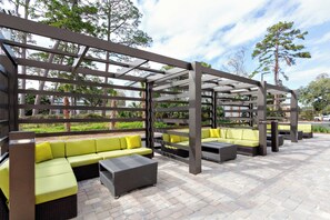 An outdoor seating area with multiple sofas and chairs, a pergola structure, and a paved floor. - Holiday Inn Tallahassee E Capitol - Univ by IHG (Tallahassee)