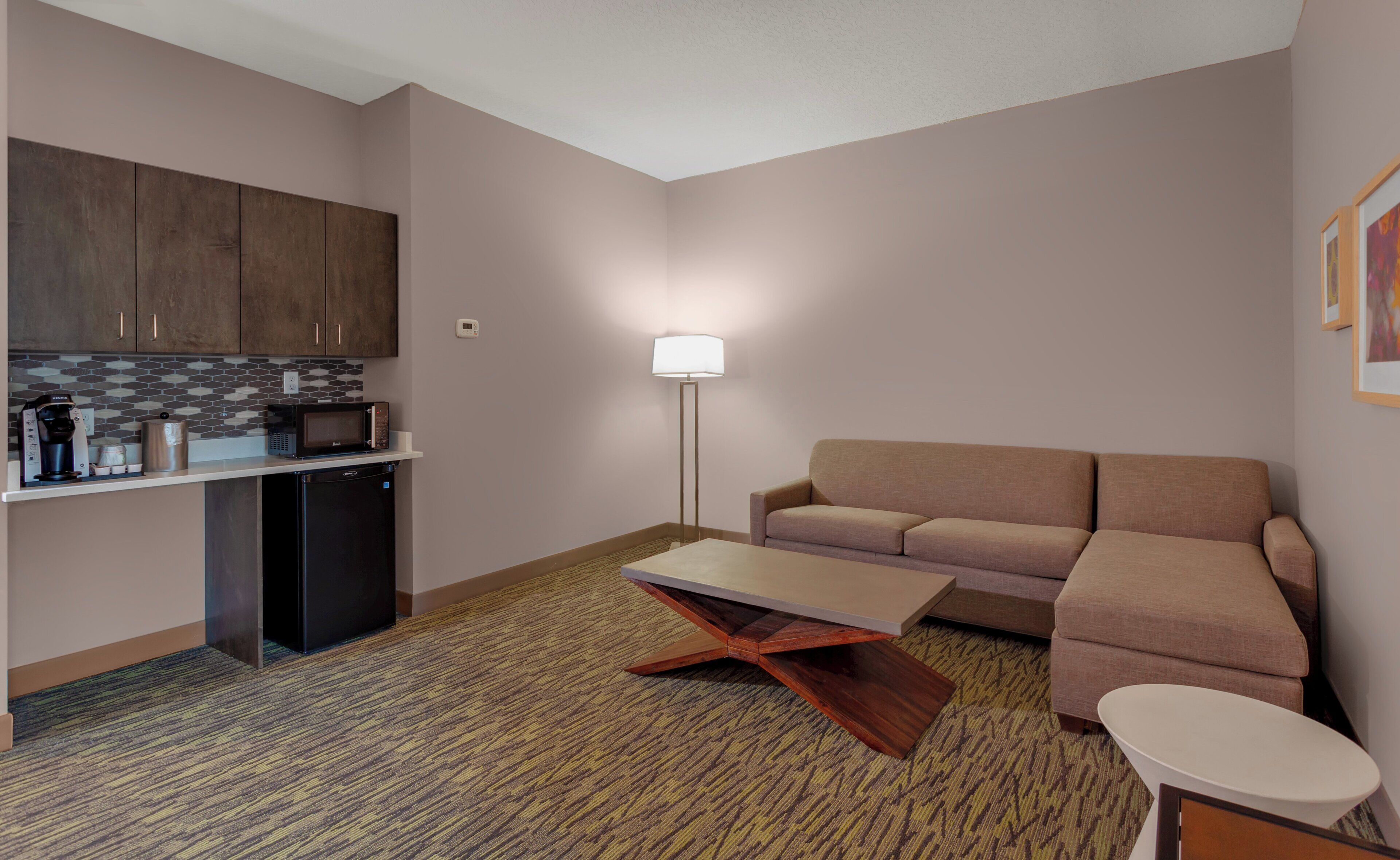 A compact living space with a kitchenette, a sofa, a coffee table, and a floor lamp.
