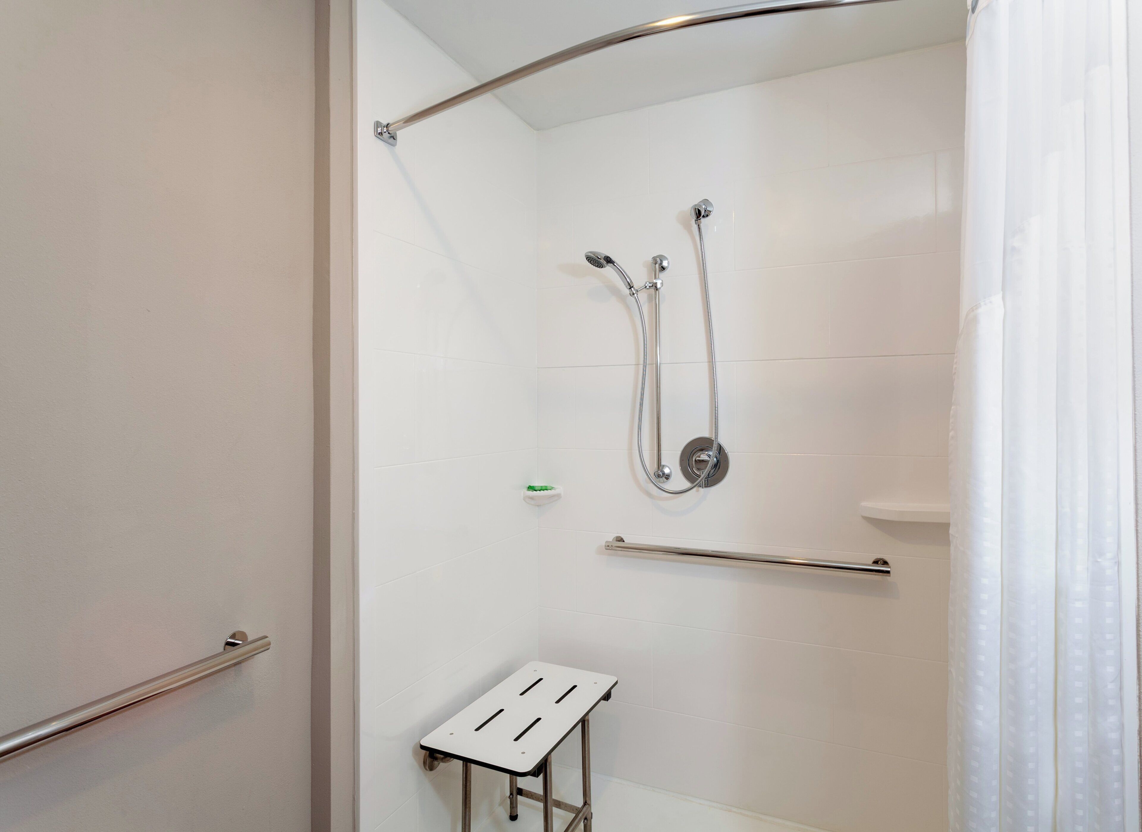 Une douche avec un pommeau de douche amovible, un pommeau de douche amovible avec un tuyau et un porte-serviettes.