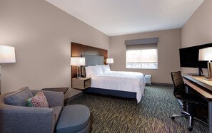 Ein Hotelzimmer mit Bett, Schreibtisch, Stuhl, einer Couch und einem Fernseher.