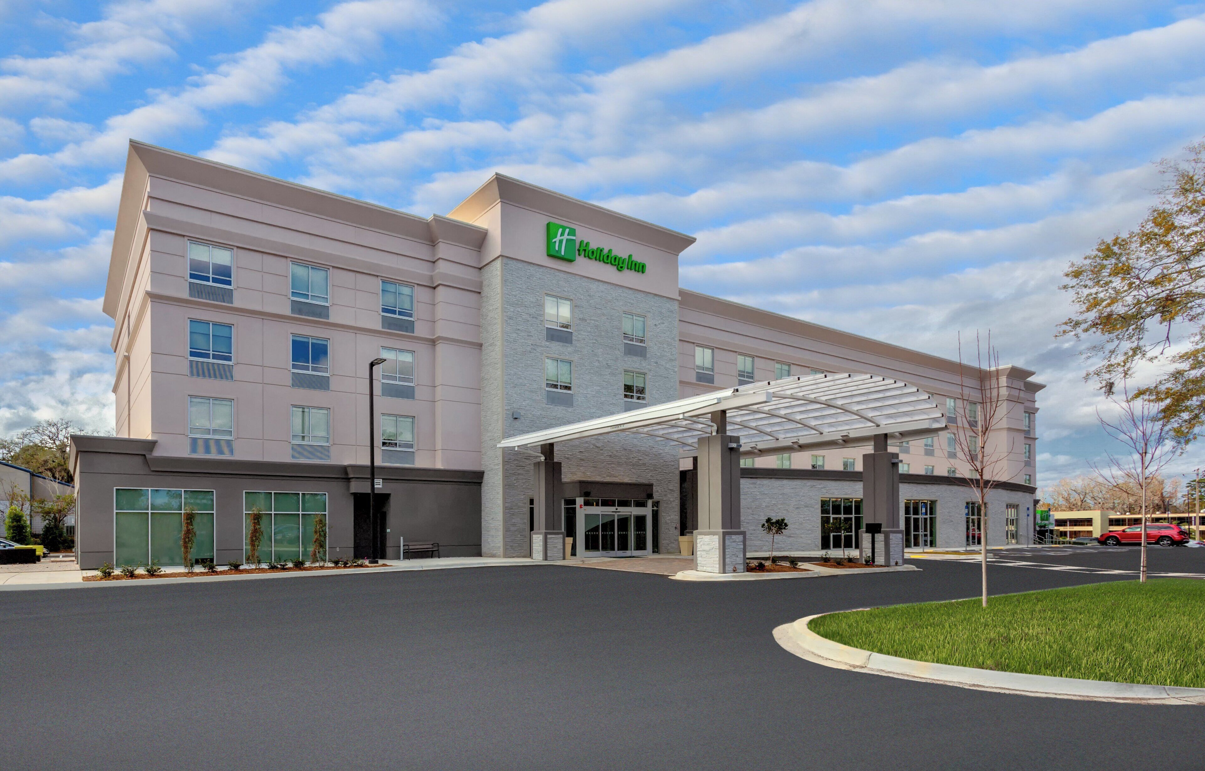 Un hôtel Holiday Inn au design moderne, doté d’une entrée couverte et de plusieurs étages.